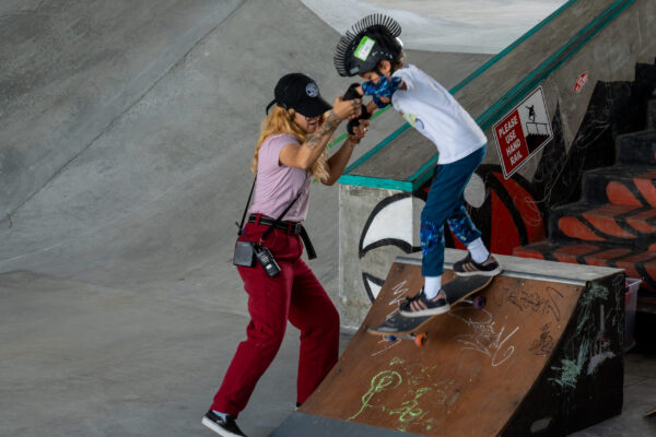 Instructor assists young child skateboarding down ramp with focused support.
