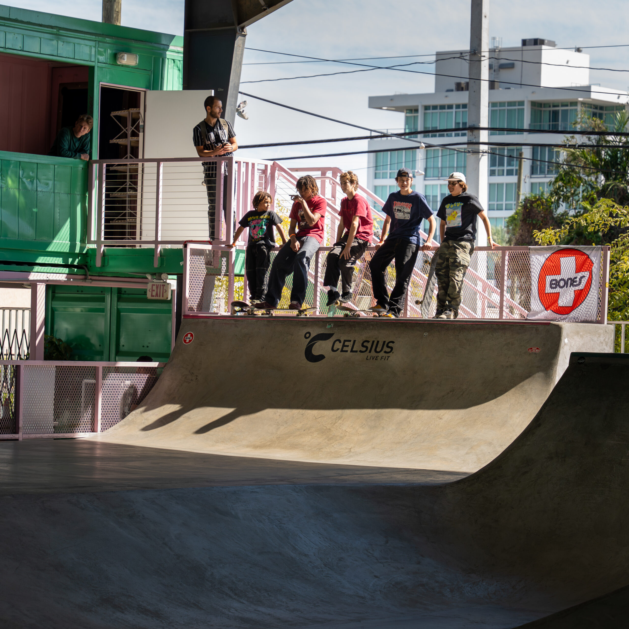 Group of teens lined up on a half-pipe, ready to drop in.