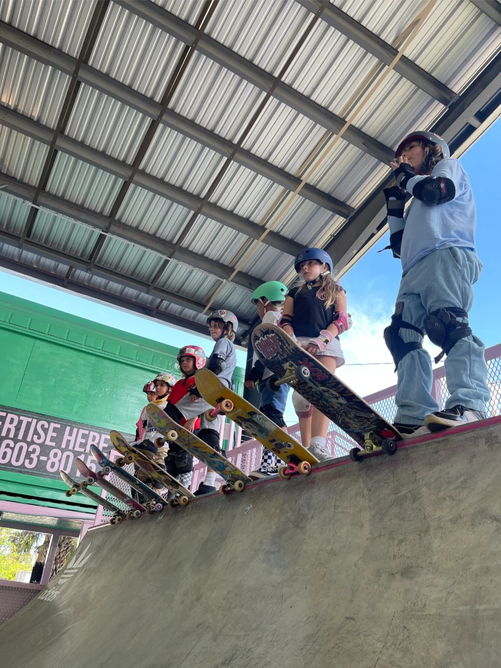 Line of young skateboarders waiting to drop in from ramp’s edge.